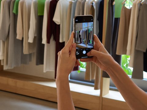 Hands photographing an outfit on a clothes rail with a phone